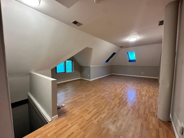 additional living space featuring vaulted ceiling and light hardwood / wood-style flooring