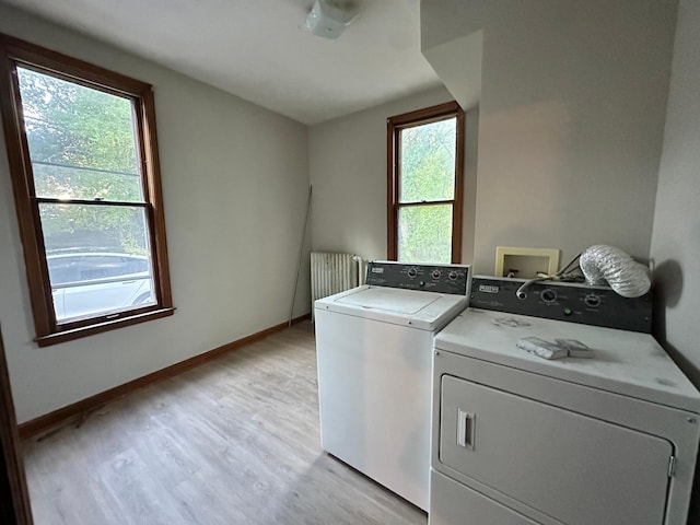 laundry area with radiator, light hardwood / wood-style flooring, and washer and dryer