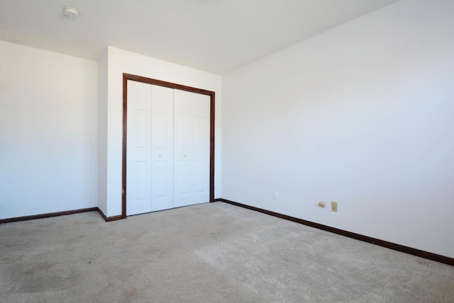 unfurnished bedroom with light colored carpet and a closet