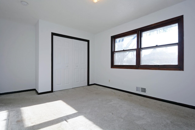 unfurnished bedroom with light colored carpet and a closet