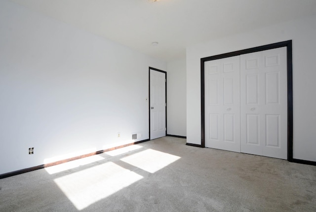 unfurnished bedroom with light carpet and a closet