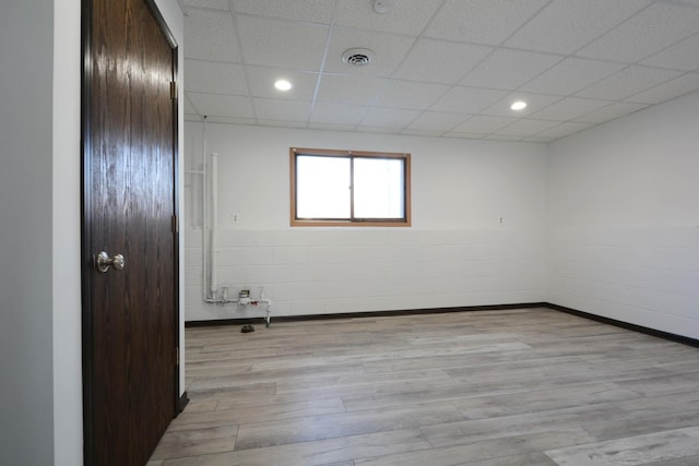 empty room with a paneled ceiling and light wood-type flooring