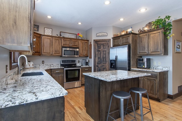 kitchen featuring stainless steel appliances, a center island, sink, and light hardwood / wood-style floors