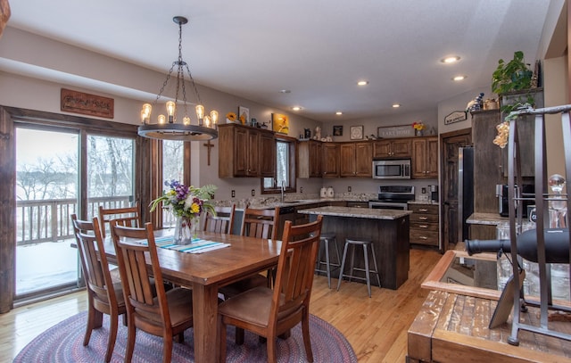 dining room with sink, an inviting chandelier, and light hardwood / wood-style floors