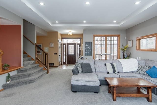 living room featuring a tray ceiling and light carpet