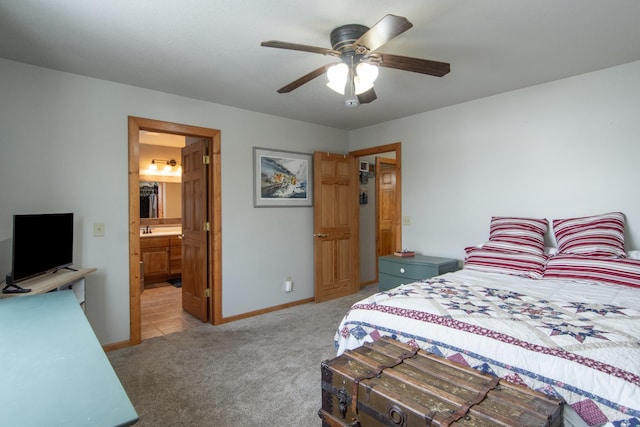 bedroom with ensuite bathroom, light colored carpet, and ceiling fan