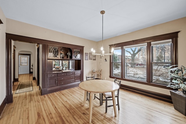 dining area with a baseboard radiator, a chandelier, and light hardwood / wood-style flooring