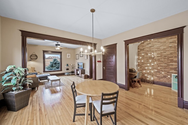 dining space with ceiling fan with notable chandelier and light wood-type flooring