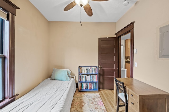 bedroom with ceiling fan, electric panel, and light wood-type flooring