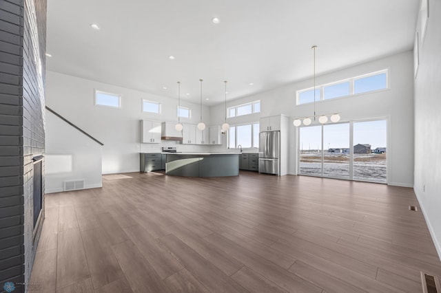 unfurnished living room with dark hardwood / wood-style flooring, sink, a brick fireplace, and a high ceiling