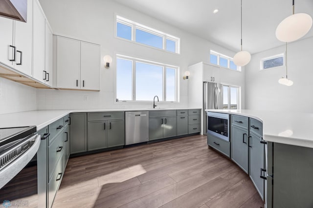 kitchen featuring stainless steel appliances, gray cabinets, white cabinets, and decorative light fixtures