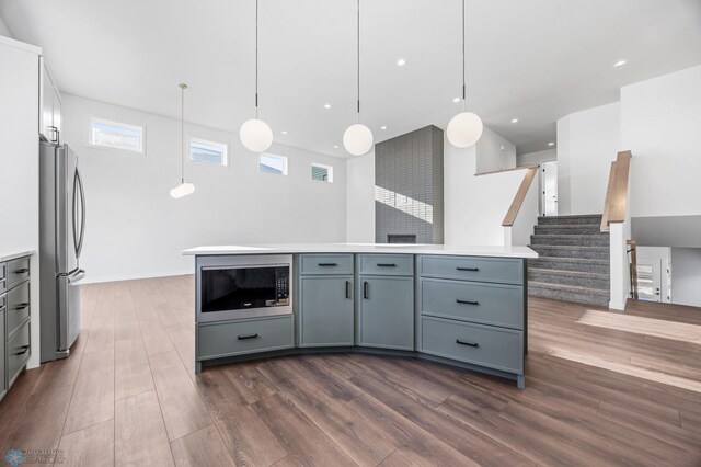 kitchen with built in microwave, dark hardwood / wood-style floors, stainless steel refrigerator, and decorative light fixtures