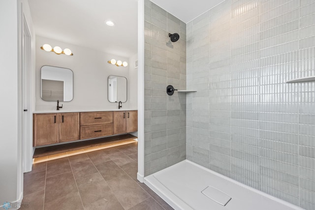 bathroom featuring tiled shower, vanity, and tile patterned flooring