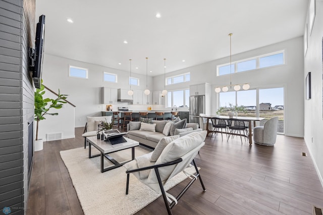 living room with dark wood-style flooring, visible vents, a wealth of natural light, and recessed lighting