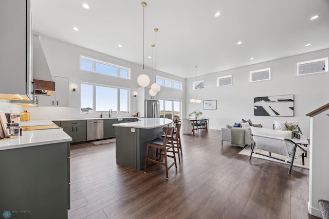 kitchen with a breakfast bar, light countertops, wall chimney exhaust hood, stainless steel appliances, and a kitchen island