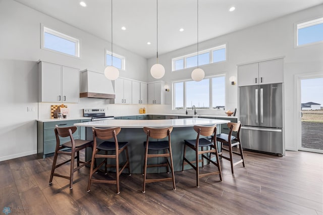 kitchen with a center island, a sink, a high ceiling, stainless steel appliances, and wall chimney exhaust hood