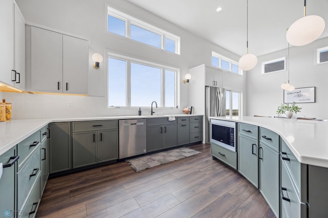 kitchen with dishwasher, dark wood finished floors, built in microwave, decorative light fixtures, and visible vents