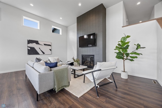 living area featuring recessed lighting, baseboards, a brick fireplace, and wood finished floors