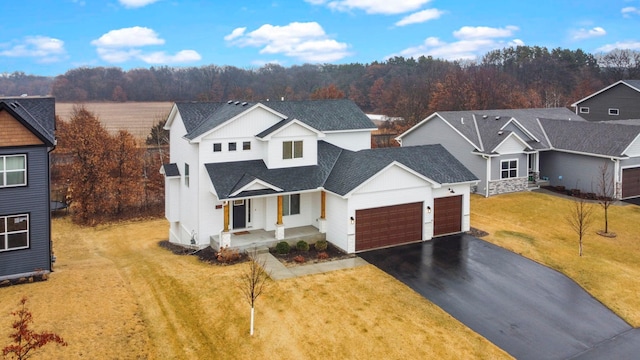 view of front facade with an attached garage, driveway, a shingled roof, and a front yard