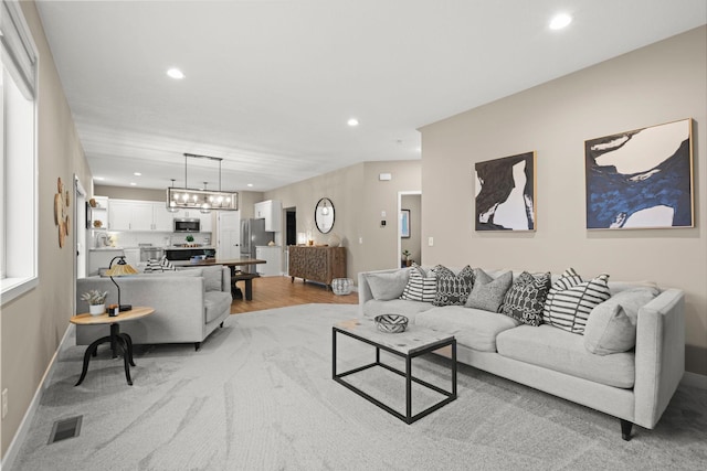 living area featuring a notable chandelier, recessed lighting, visible vents, light wood-style flooring, and baseboards