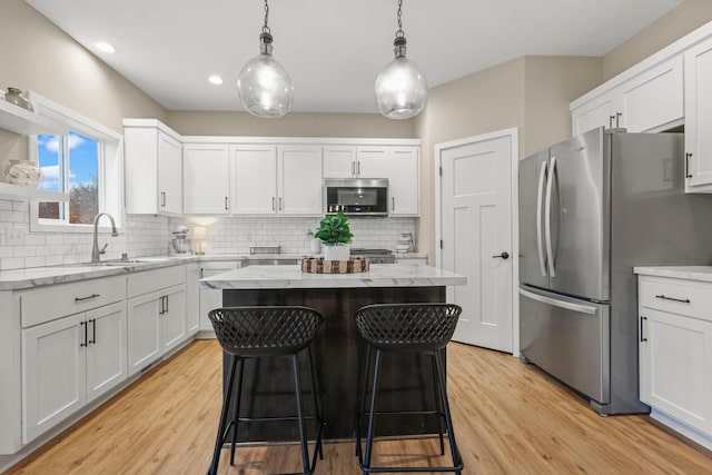 kitchen with appliances with stainless steel finishes, a kitchen island, a sink, and white cabinetry