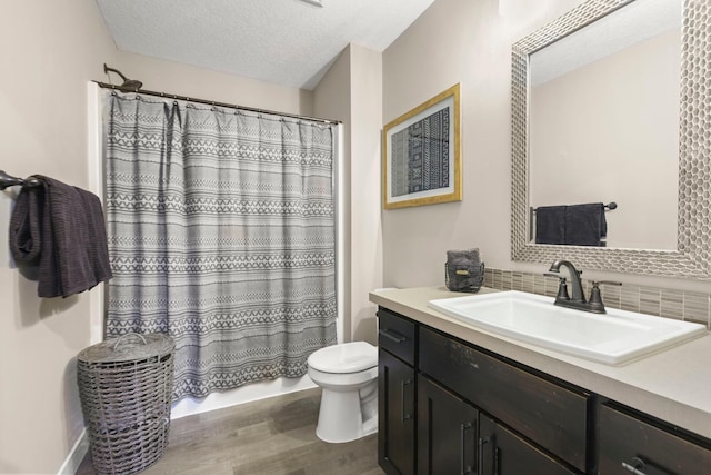 bathroom with tasteful backsplash, toilet, vanity, a textured ceiling, and wood finished floors