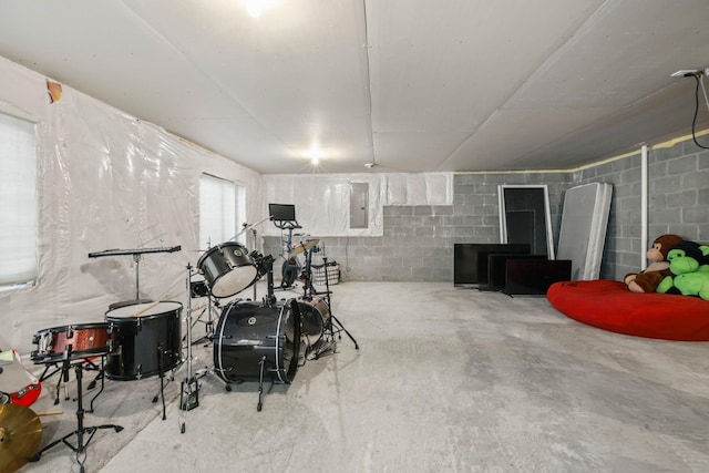 recreation room featuring concrete block wall, electric panel, and unfinished concrete floors