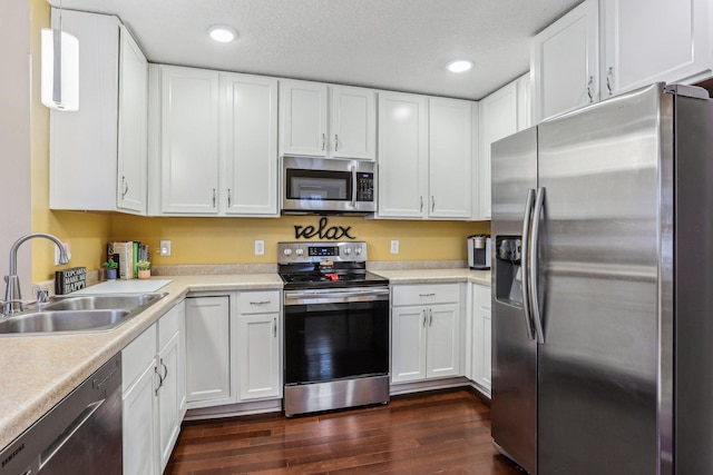 kitchen with pendant lighting, sink, stainless steel appliances, and white cabinets