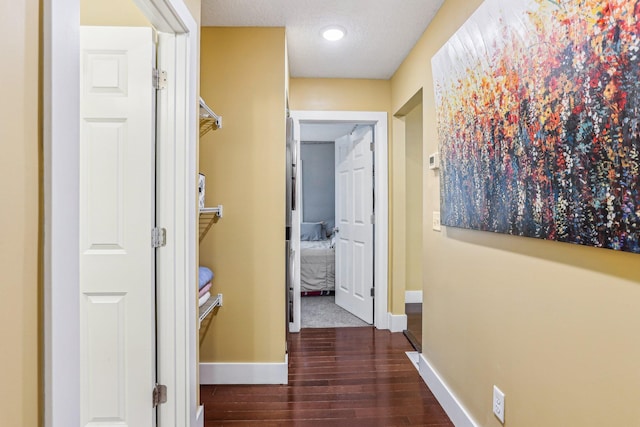 corridor with dark hardwood / wood-style floors and a textured ceiling