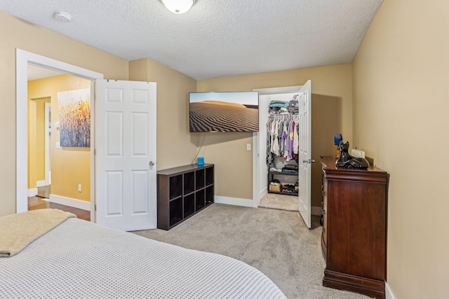 bedroom with light colored carpet, a textured ceiling, and a closet