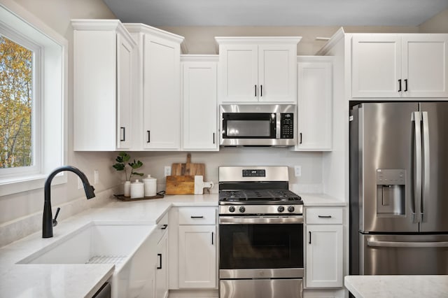 kitchen featuring white cabinetry, sink, stainless steel appliances, and light stone countertops