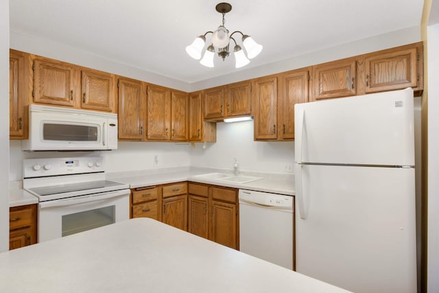 kitchen featuring a notable chandelier, sink, white appliances, and decorative light fixtures