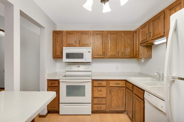 kitchen featuring sink, white appliances, and light wood-type flooring