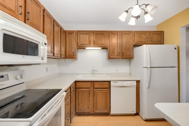 kitchen with sink, a chandelier, white appliances, and light hardwood / wood-style flooring