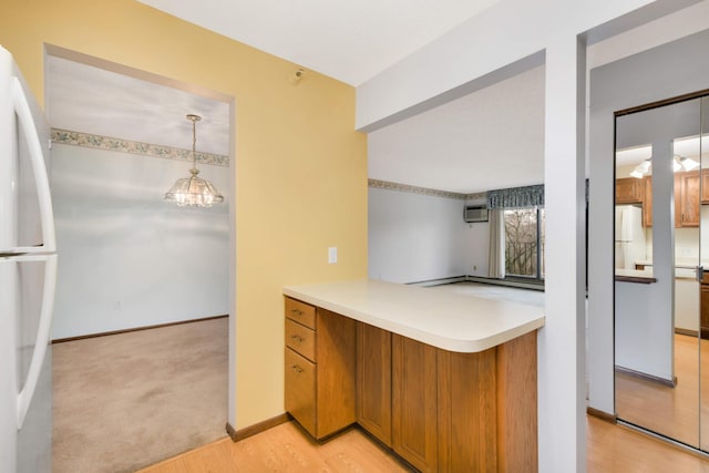 kitchen featuring white refrigerator, hanging light fixtures, a chandelier, and light wood-type flooring