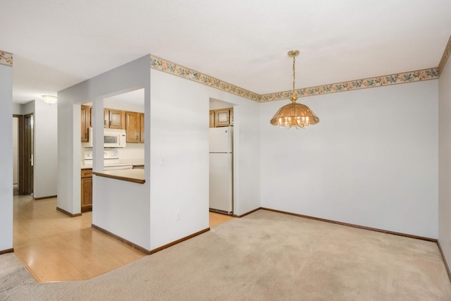 kitchen featuring an inviting chandelier, light colored carpet, white appliances, and decorative light fixtures