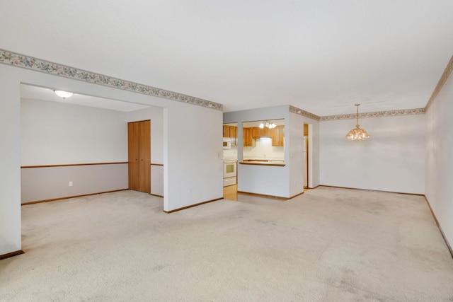 unfurnished living room with an inviting chandelier and carpet flooring