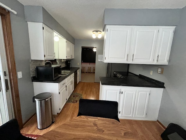 kitchen with white cabinetry, dishwasher, and a textured ceiling