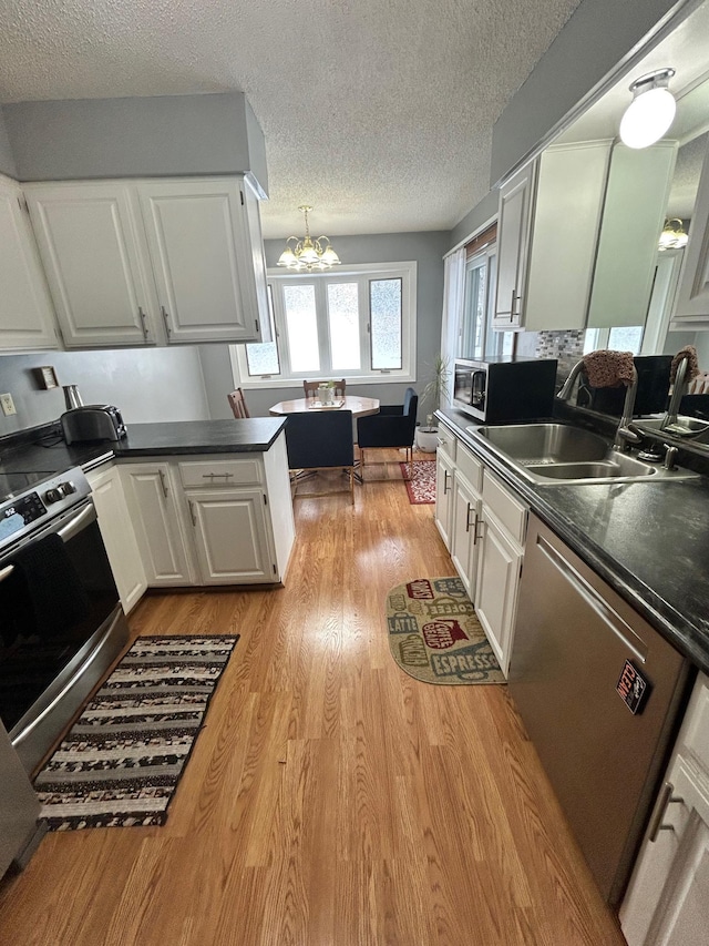 kitchen featuring sink, light hardwood / wood-style flooring, stainless steel appliances, a textured ceiling, and white cabinets