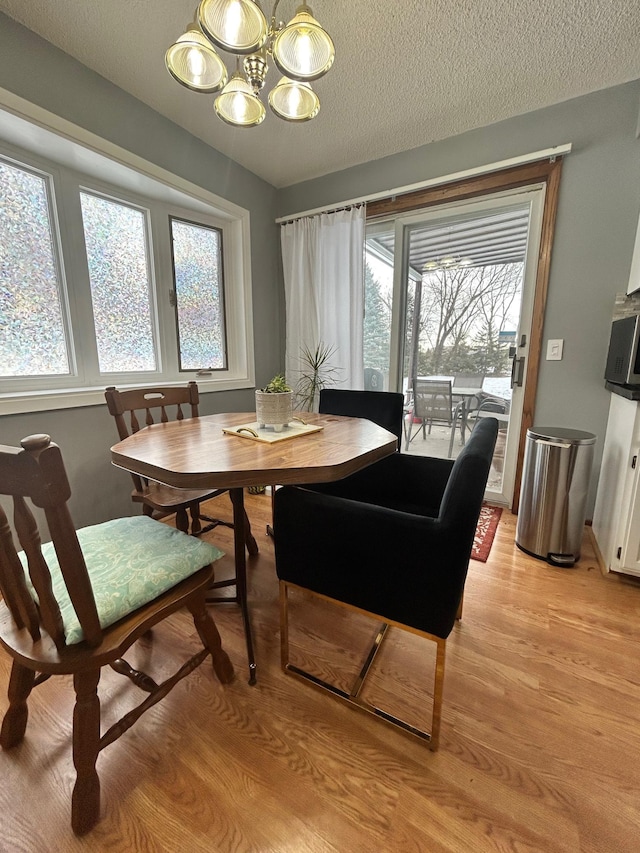 dining room featuring a chandelier, a textured ceiling, and light hardwood / wood-style flooring