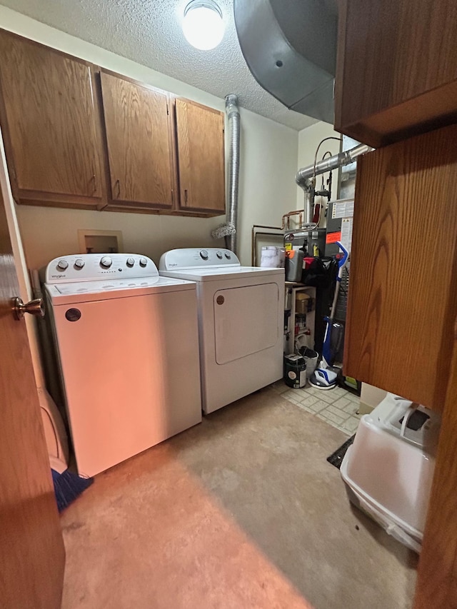 washroom with cabinets, washing machine and dryer, and a textured ceiling