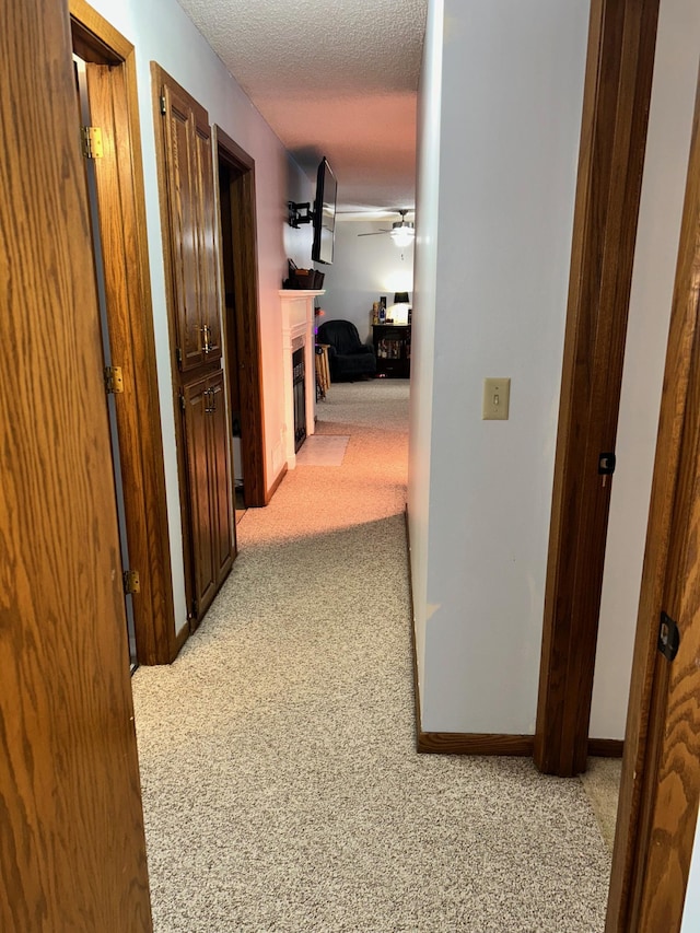 corridor with light colored carpet and a textured ceiling