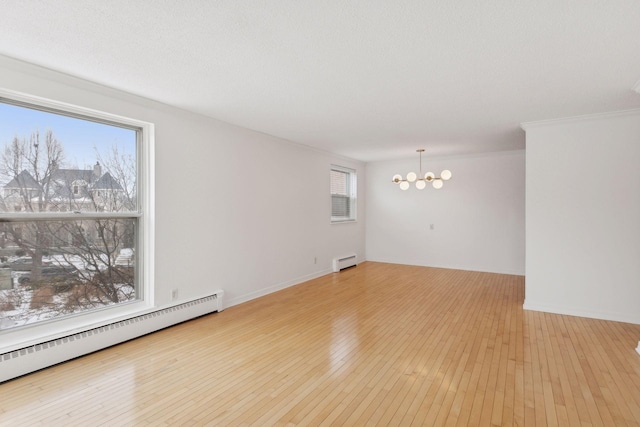 spare room with a baseboard heating unit, a notable chandelier, light hardwood / wood-style flooring, and a textured ceiling