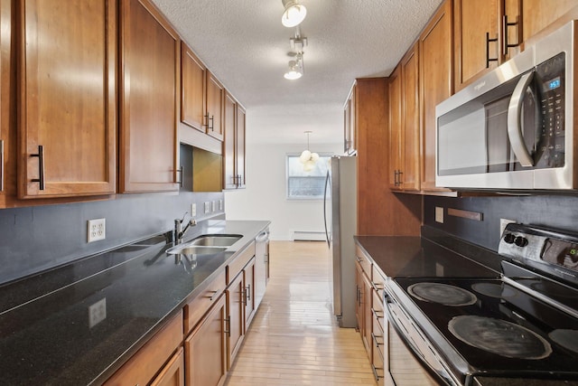 kitchen with pendant lighting, sink, light hardwood / wood-style flooring, appliances with stainless steel finishes, and a baseboard radiator