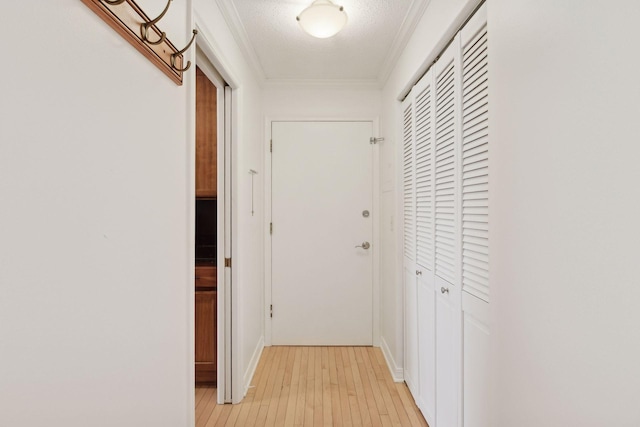 hall featuring crown molding, light hardwood / wood-style flooring, and a textured ceiling