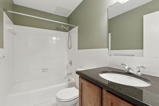 full bathroom featuring tile walls, vanity, tiled shower / bath, and toilet