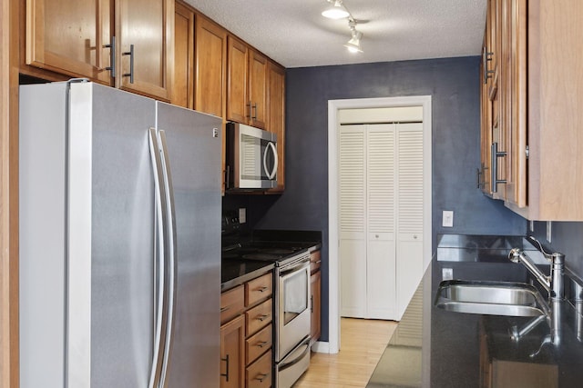 kitchen with sink, light hardwood / wood-style flooring, stainless steel appliances, and a textured ceiling