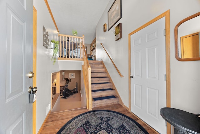 foyer with stairs, visible vents, and wood finished floors