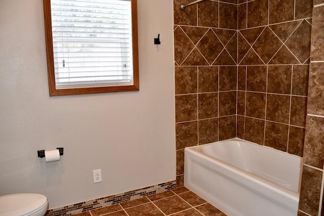 bathroom with tile patterned floors, washtub / shower combination, and toilet