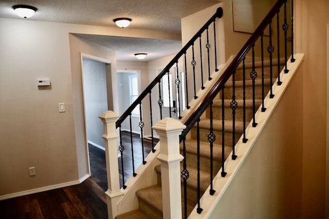 stairs featuring wood-type flooring and a textured ceiling